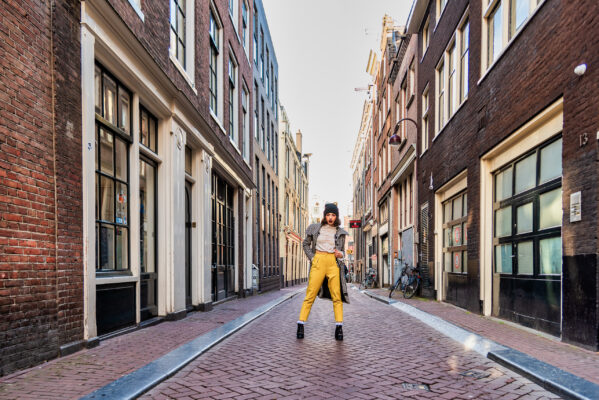 Destination photographer Amsterdam — traveller leaping along a quiet canal street lined with bicycles