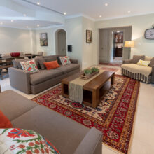 Real estate photography of a bright living room with twin sofas, coffee table, and patterned rug