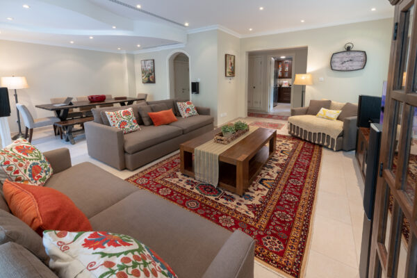 Real estate photography of a bright living room with twin sofas, coffee table, and patterned rug