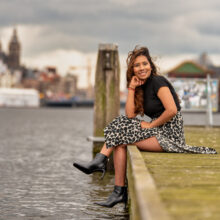 Outdoor portrait of woman in floral skirt seated on quay near Nemo Science Museum, Amsterdam