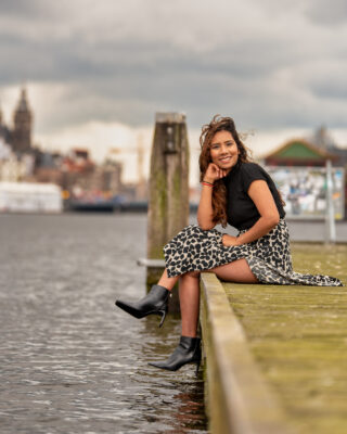 Outdoor portrait of woman in floral skirt seated on quay near Nemo Science Museum, Amsterdam