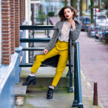 Travel portrait of woman in yellow trousers on Amsterdam canal-house steps — visiting traveller shoot