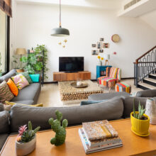 Real estate photography of an open-plan living room with sectional sofa, staircase, and floor-to-ceiling windows