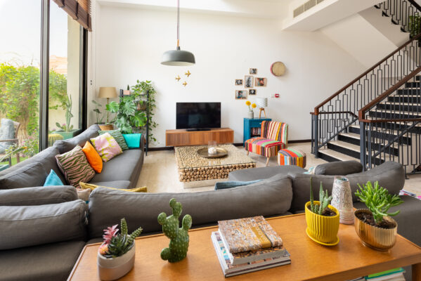 Real estate photography of an open-plan living room with sectional sofa, staircase, and floor-to-ceiling windows