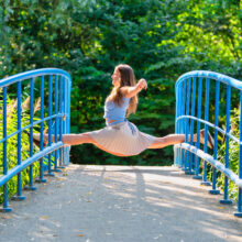 Lifestyle photographer Amsterdam — woman performing mid-air leap on blue bridge in Vondelpark