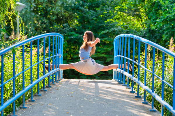 Lifestyle photographer Amsterdam — woman performing mid-air leap on blue bridge in Vondelpark