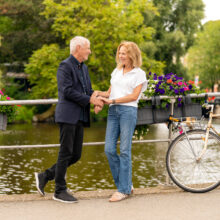 Travel portrait of couple on a flower-decorated Amsterdam canal bridge — visiting travellers shoot