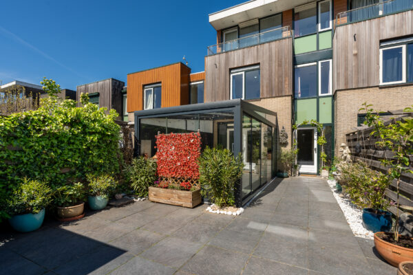 Real estate photography of a modern townhouse exterior with planted terrace and timber cladding