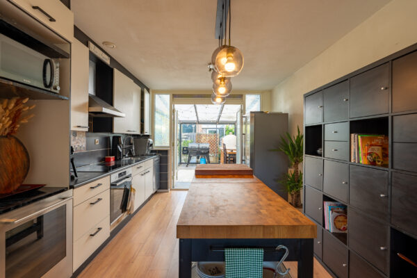 Real estate photography of a modern dark kitchen with pendant lighting and adjoining dining area