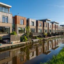 Real estate photographer Amsterdam — modern townhouses along a residential canal with water reflection