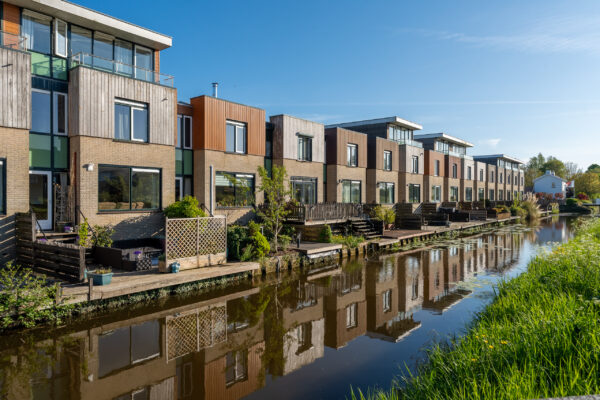 Real estate photographer Amsterdam — modern townhouses along a residential canal with water reflection