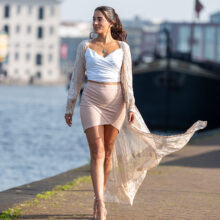 Walking portrait of woman in white top and pink skirt along the quay near Het Scheepvaartmuseum