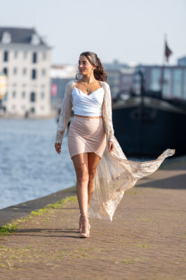 Walking portrait of woman in white top and pink skirt along the quay at Het Scheepvaartmuseum, Amsterdam