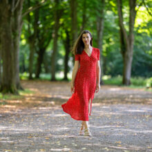 Portrait photographer Amsterdam — woman in red dress on tree-lined path in Amsterdamse Bos