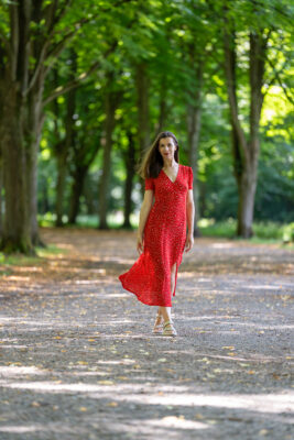 Portrait photographer Amsterdam — woman in red dress on a tree-lined path in Amsterdamse Bos