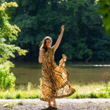 Forest portrait of woman in patterned dress with arms raised, Amsterdamse Bos