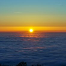 Photo showing the sunset from above the clouds from a mountain.
