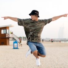 Photo of a hip hop dancer jumping in the air on a beach in Amsterdam with the Burj Al Arab in the background.