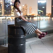 Photo of a girl in A fashionably-dress woman in a skirt smiling as she sits on top of barrel in Dubai.